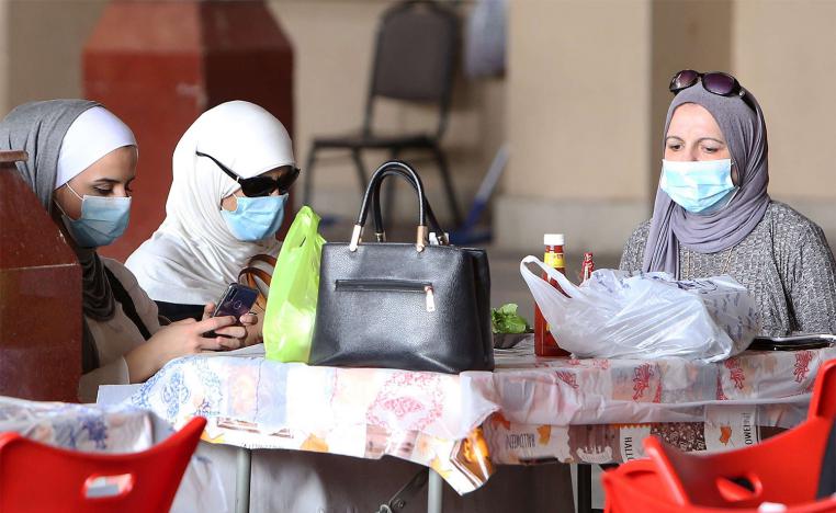 Kuwaiti women wear protective masks as they sit in a restaurant inside the Mubarakiya Market in Kuwait City 