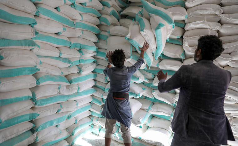 Workers handle sacks of wheat flour at a World Food Programme food aid distribution center in Sanaa