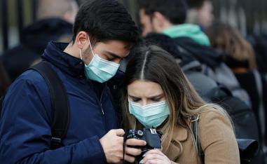 زوجان يرتديان كمامات أثناء نظرهما إلى صورهما بعد زيارة قصر باكنغهام في لندن 