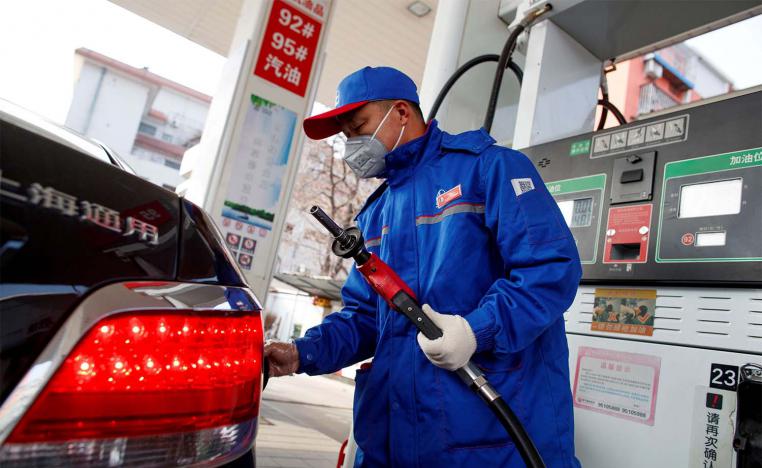A pump attendant wears a mask as he refuels a car at a Sinopec gas station in Beijing