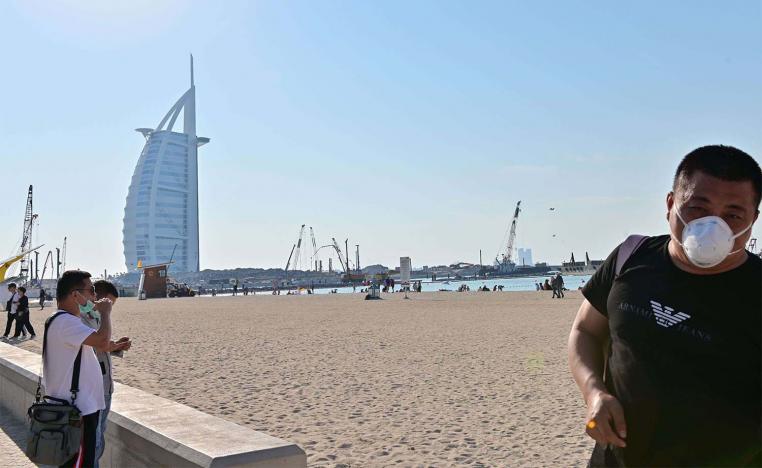 Tourists wearing surgical are pictured on a beach next to Burj Al Arab
