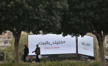 جلان يمران أمام لوحات إعلانية تعرض رسالة تحث المواطنين على البقاء في منازلهم في بيروت