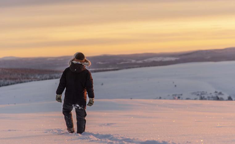 راع لحيوان الرنة يسير عبر الثلج في منطقة القطب الشمالي بالسويد