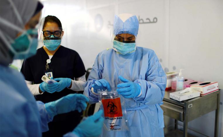 A member of medical staff wearing a protective face mask and gloves carries a swab tested during drive-thru coronavirus disease testing (COVID-19) at a screening centre in Abu Dhabi