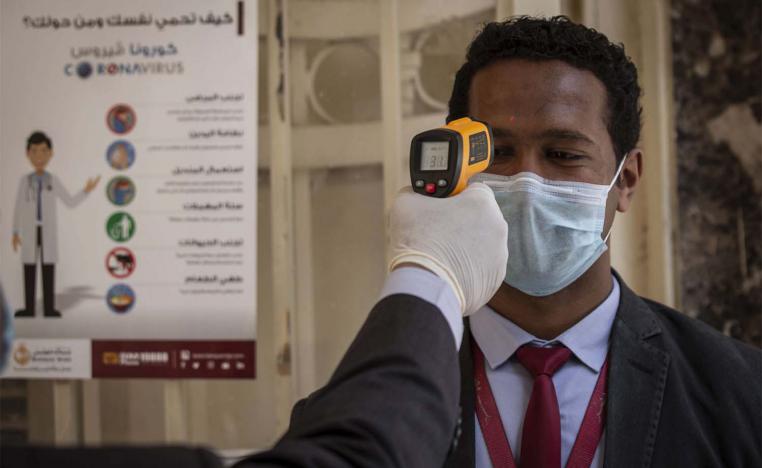 An employee has his body temperature checked before entering the Egyptian bank 'Banque Misr' headquarters