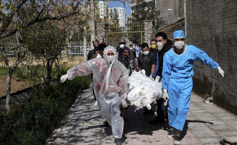People carry the body of a victim who died after being infected with the new coronavirus at a cemetery just outside Tehran