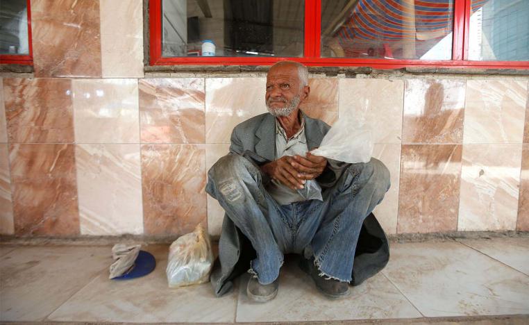 An Iraqi homeless man sits in front of a closed restaurant, during a curfew imposed to prevent the spread of coronavirus disease in Basra
