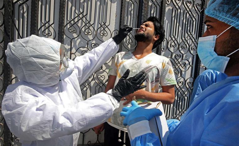 Iraqi public hospital specialised doctors test a resident for COVID-19 in the capital Baghdad's suburb of Sadr City