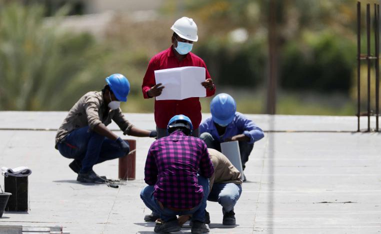 Workers wearing protective face masks work on a residential construction site in Dubai