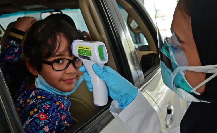 A nurse measures the body temperature of a young girl at a drive thru testing centre for COVID-19 in Abu Dhabi