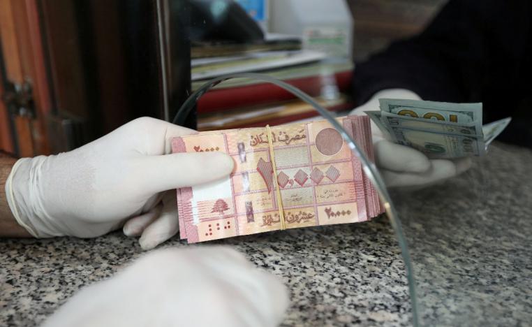 A customer wearing gloves holds Lebanese pounds at a currency exchange store