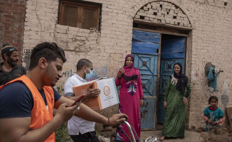 NGO workers distribute cartons filled with food to people in Cairo, Egypt