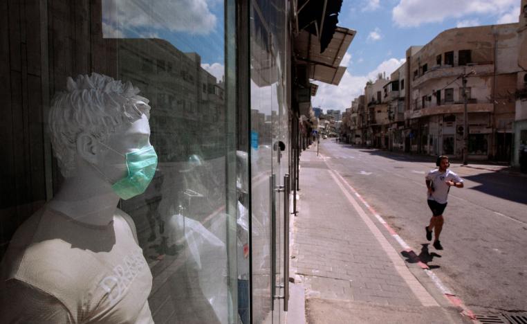 A man runs on an empty street next to a shop in Tel Aviv, Israel