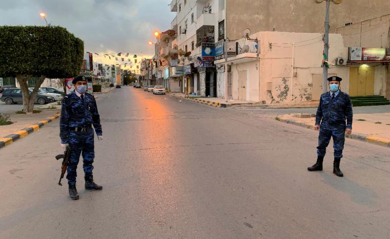 Libyan policemen wearing protective masks, stand guard on a street during a curfew in Misrata, Libya