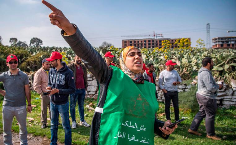 A woman wearing a vest with the slogan "long live the King, down with the real estate mafia", chants slogans during a demonstration against the "Bab Darna" real estate group in Casablanca