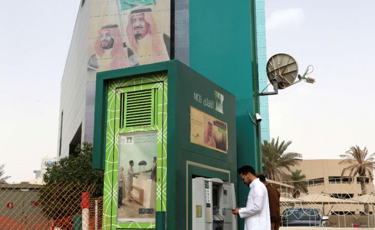 A man withdraws money from an ATM outside the Saudi National Commercial Bank