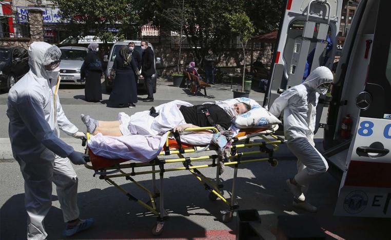 Medics wearing masks and suits against the coronavirus, take a patient out of an ambulance