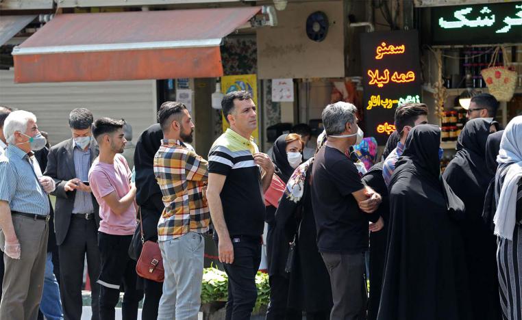 Iranians, wearing protective masks without observing social distancing, queue outside a money exchange office in Tehran