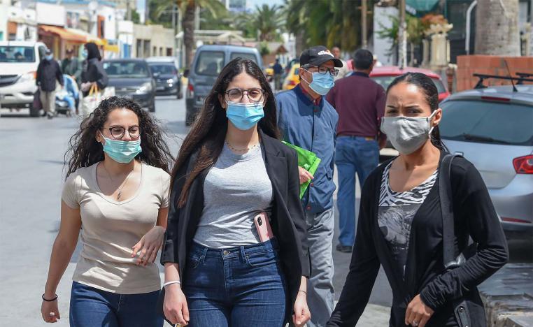 Tunisians wearing protective masks amid the COVID-19 pandemic walk by 
