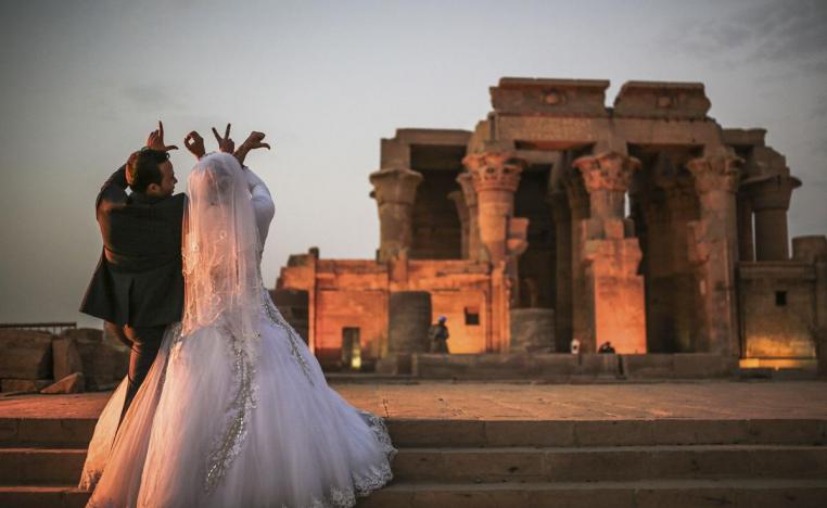 زوجان مصريان يحتفلان بزفافهما أمام معبد في أسوان