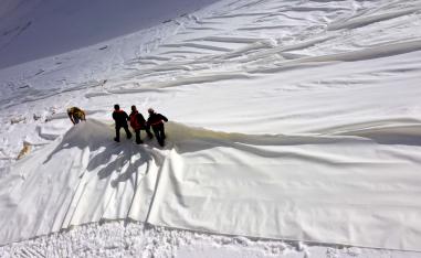 عمال يغطون بقماش أبيض نهر بريسينا الجليدي