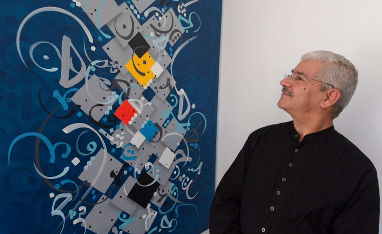 الخطاط التونسي عمر الجمني ينظر إلى أعماله الفنية بالخط العربي في منزله 