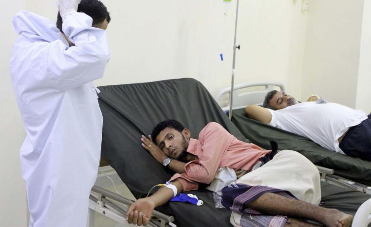 Yemeni doctor talks to a patient receiving treatment and lying on a bed at a hospital in Aden