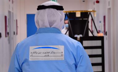 خبير اماراتي يرتدي شعار مركز الشيخ محمد بن راشد للفضاء يسير باتجاه نموذج لخليفة سات