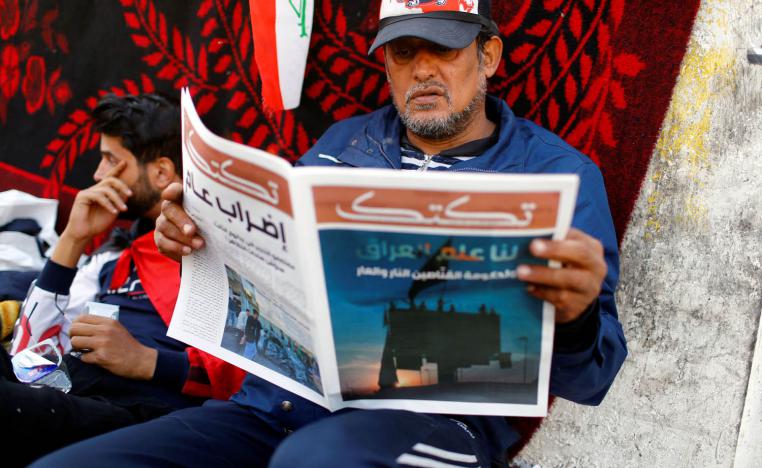 عراقي يقرأ صحيفة وسط ساحة التحرير في بغداد