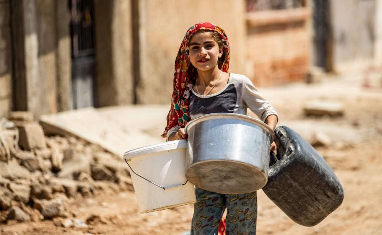 فتاة سورية تندفع لملء الماء من صهاريج قدمتها المنظمات الإنسانية