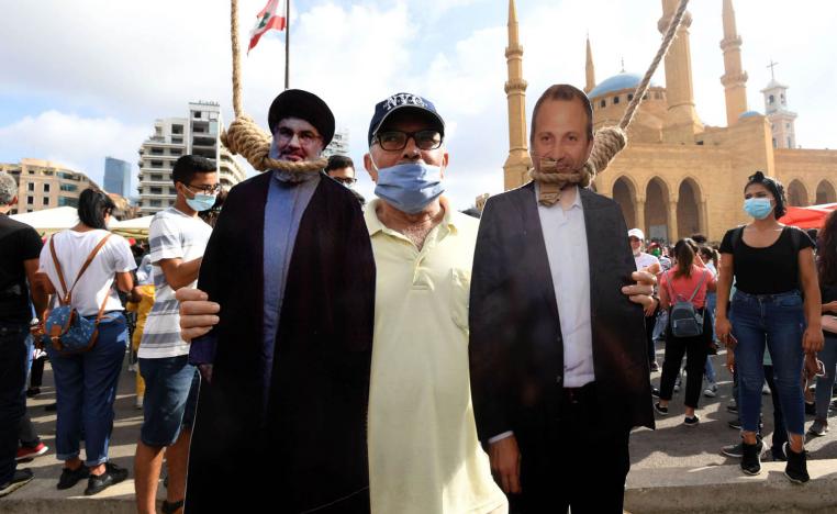 لبناني يحمل صورتين لجبران باسيل وحسن نصرالله معلقتين من حبال مشنقة