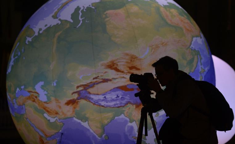 مصور يقف أمام كرة أرضية مضيئة 