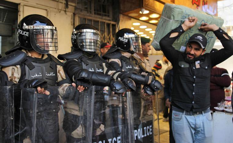 عراقي ينقل عملة ورقية عراقية إلى البنك بحماية قوات الأمن