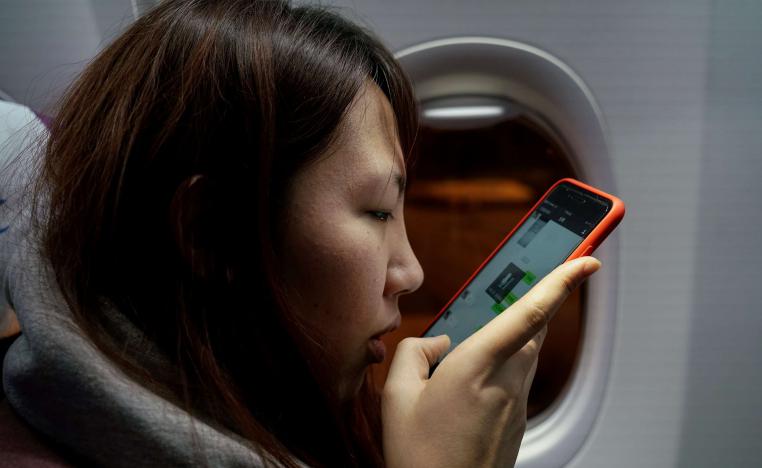 مسافرة صينية تستخدم هاتفها في الطائرة