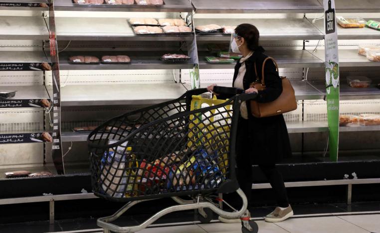 متسوقة لبنانية تتجول في سوبرماركت بأرفف شبه فارغة