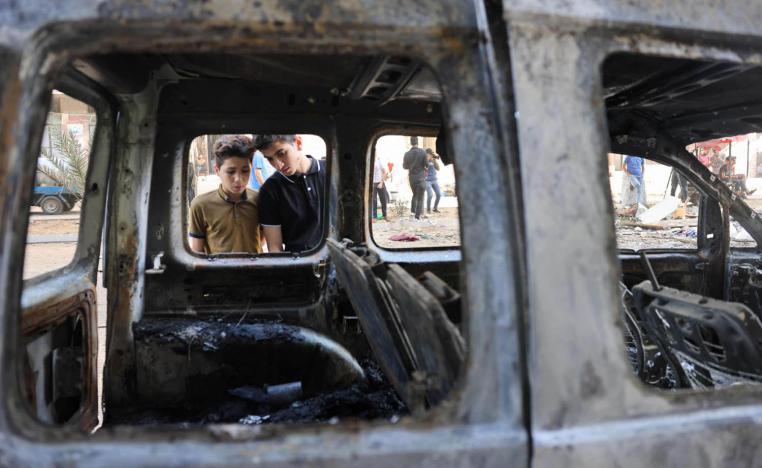 اطفال فلسطينيون ينظرون إلى سيارة محترقة بعد جولة قصف إسرائيلي على غزة
