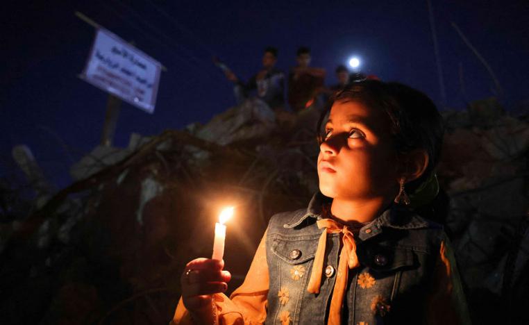 طفل فلسطيني يوقد شمعة على اطلال القصف في غزة