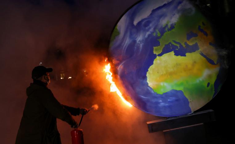 ناشط يطفئ كرة أرضية محترقة من الورق خلال مظاهرة ضد صناعة الوقود الأحفوري في ألمانيا