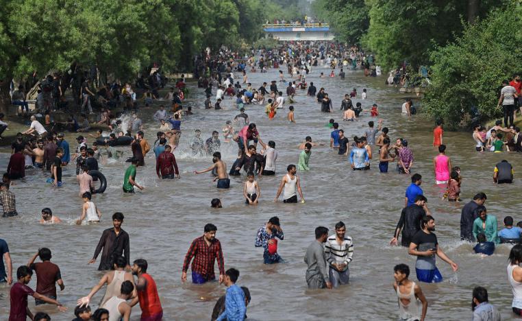 باكستانيون يبردون أنفسهم في قناة في يوم صيفي حار في لاهور في مايو 2021
