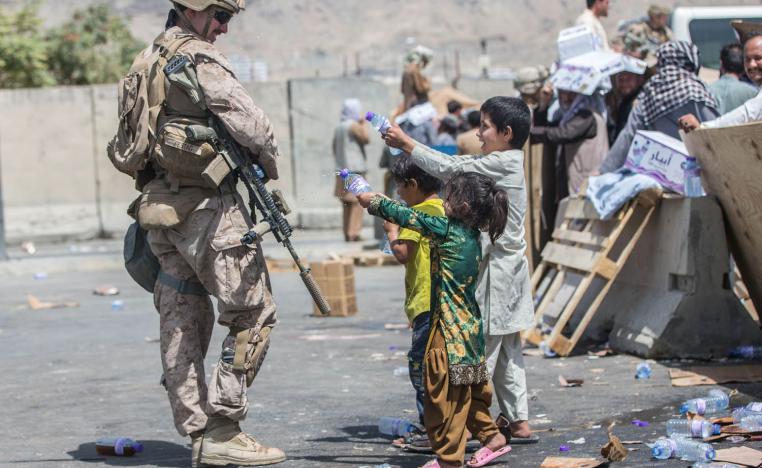 اطفال افغان يعرضون قوارير الماء على جندي أميركي