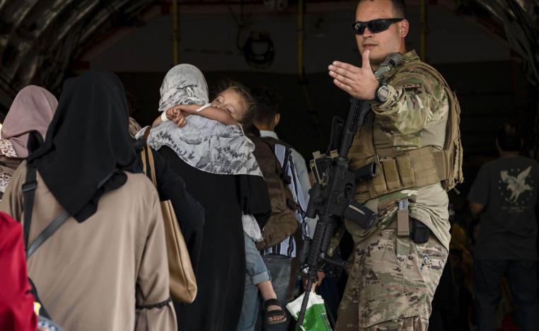 جندي أميركي يوجه لاجئين أفغان للصعود في طائرة عسكرية