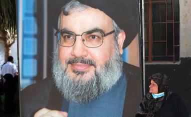 لبنانية تجلس بالقرب من جدارية لحسن نصرالله