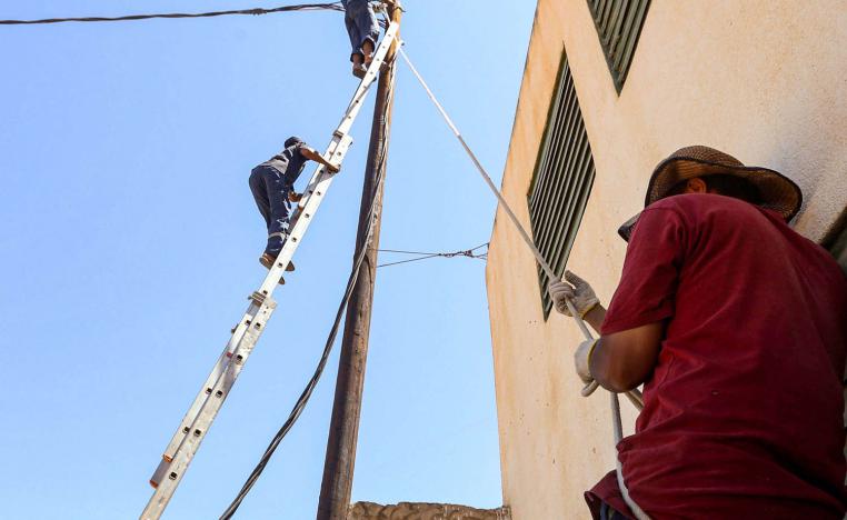 عمال ليبيون يصلحون خط كهرباء في طرابلس