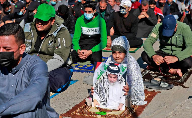 طفلة تحمل صورة الصدر اثناء الصلاة في بغداد