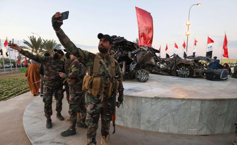 عناصر من الحشد يلتقطون صور سيلفي قرب موقع قتل فيه سليماني والمهندس حيث وضع هيكل محترق للسيارة التي كانت تقلّهما