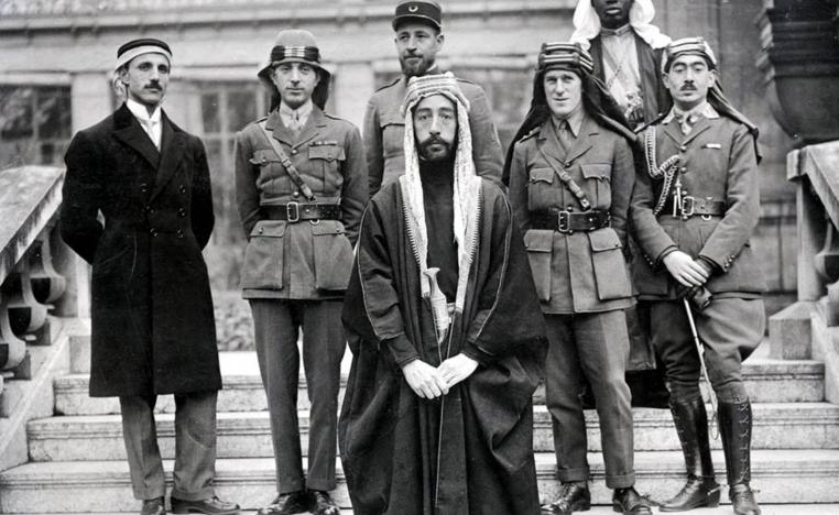 الملك فيصل ويظهر خلفه الأول من اليمين تحسين قدري وتوماس إدوارد لورنس ثم نوري السعيد ورستم حيدر