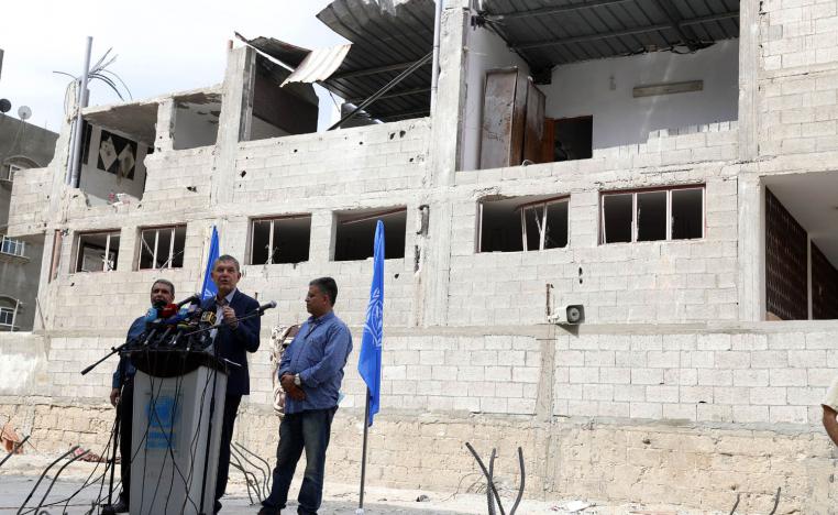 موظفو الاونروا في غزة امام أحد المنازل المدمرة