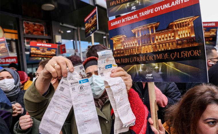 A woman displays her utility bills during a protest against high energy prices in Istanbul
