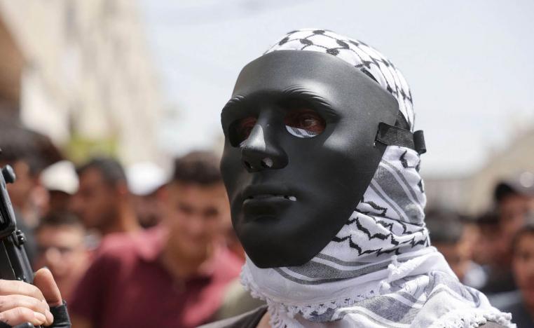 فلسطيني يرتدي قناعا خلال جنازة لناشط فلسطيني في الضفة الغربية