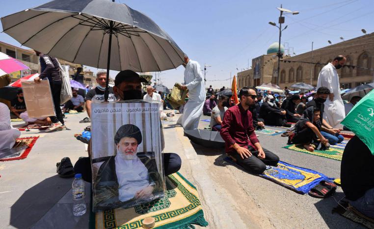 عراقيون يرفعون صورا للصدر أثناء صلاة الجمعة في مدينة الصدر في بغداد